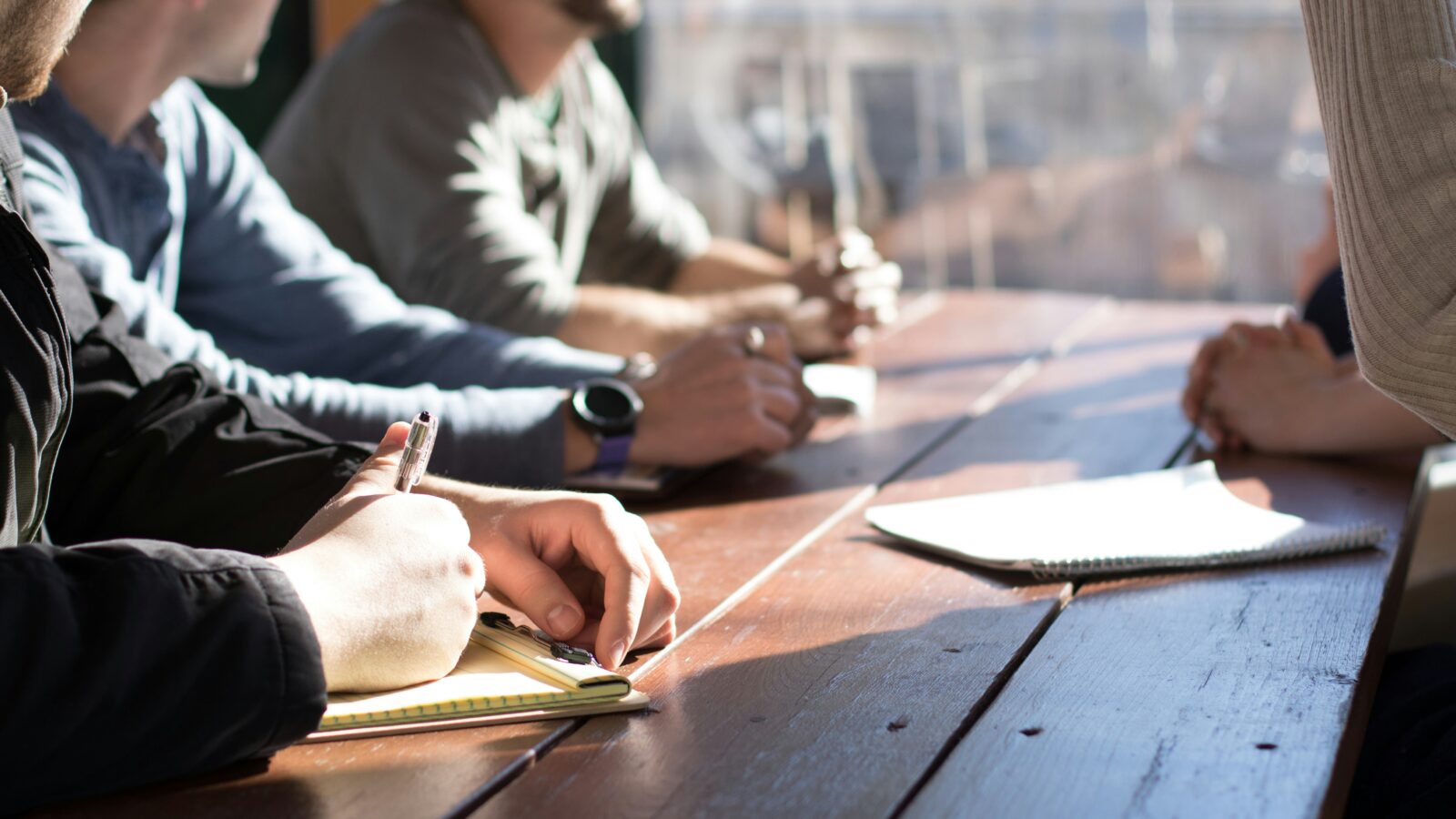 Hands taking notes on wooden table