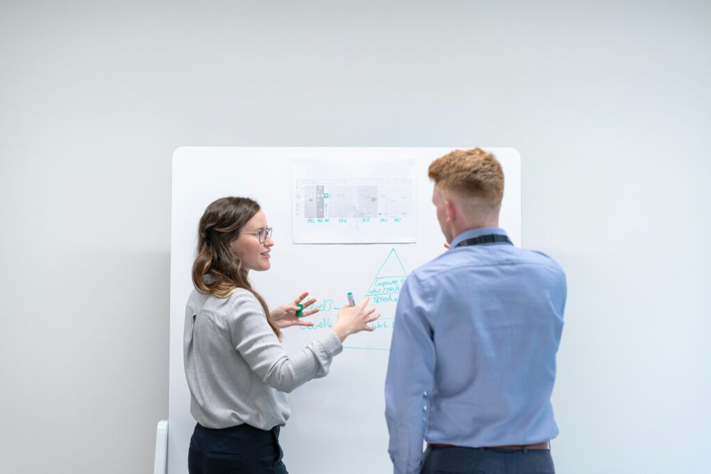 Woman explaining process to man using whiteboard